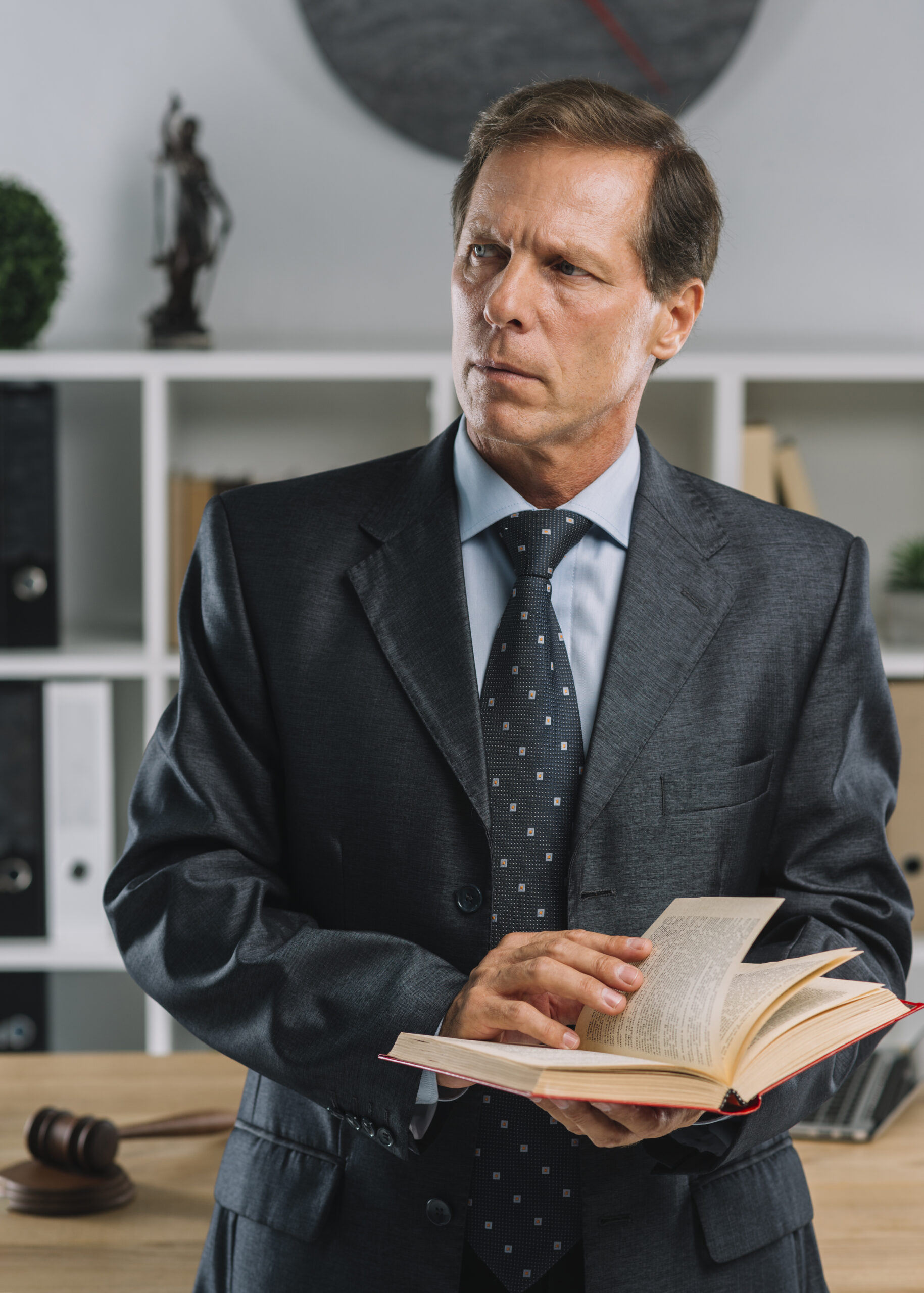 close-up-mature-lawyer-holding-law-book-looking-away-courtroom close-up-mature-lawyer-holding-law-book-looking-away-courtroom